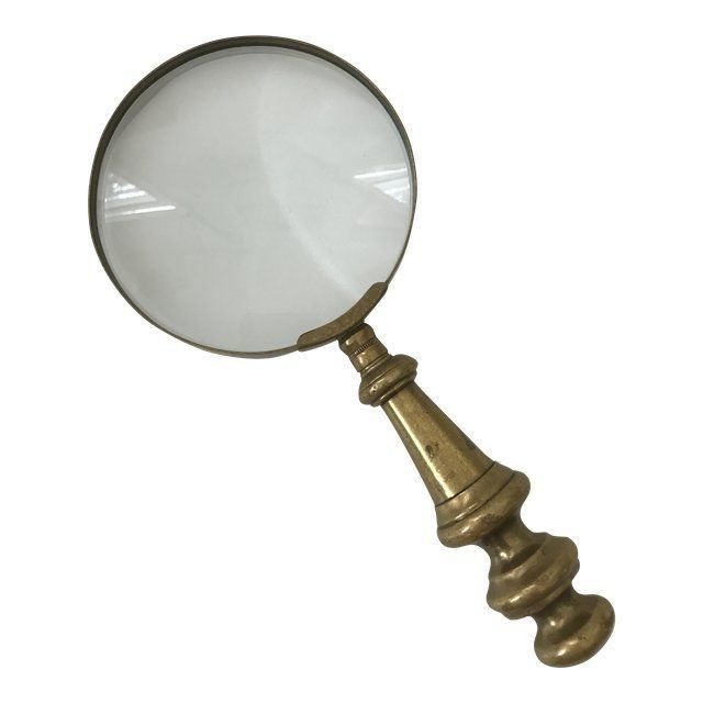 Antique brass magnifying glass resting over a handwritten note